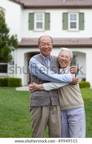 Happy Smiling Chinese Elderly Couple Standing in front of New House Hugging