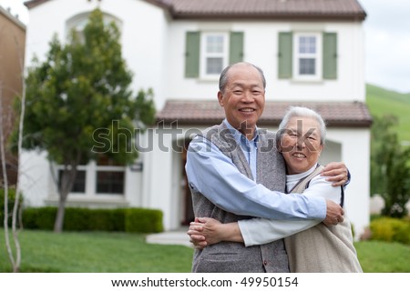 Happy Smiling Chinese Elderly Couple Standing in front of New House