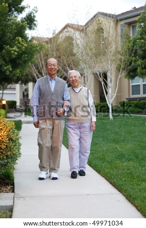 Happy Smiling Chinese Elderly Couple Walking in Residential Community