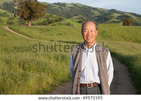 Happy Smiling Chinese Elderly Standing in front of Farmland