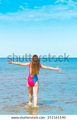 Back view of a woman wading in the sea.