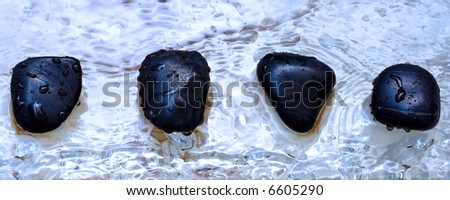 four volcanic polished stones in zen composition on wet water drops marble surface