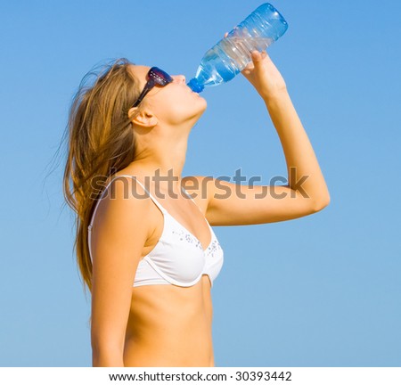 Girl drinking water on a hot day by a sea