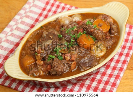 Beef bournguignon stew in rustic serving dish.