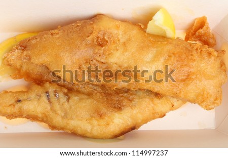 Fried cod fish in batter in cardboard takeaway carton.
