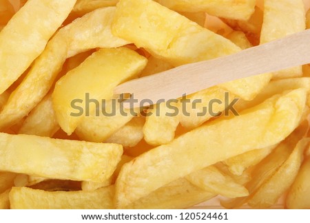 Potato chips in takeaway carton with wooden chip fork.