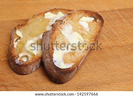 Two slices of toasted artisan bread with melting butter.