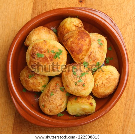 Roast potatoes in terracotta serving dish.