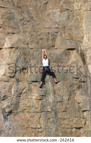 Female climber ascending sheer cliff face