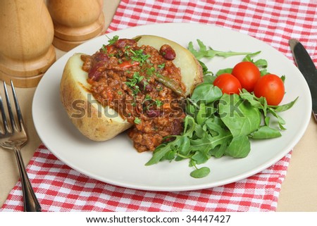 Jacket potato with chilli con carne and herb leaf salad