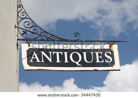 Old, rusty \'Antiques\' wall sign on wrought iron bracket