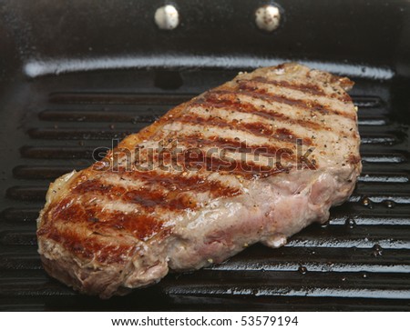 Seasoned sirloin steak in griddle pan.