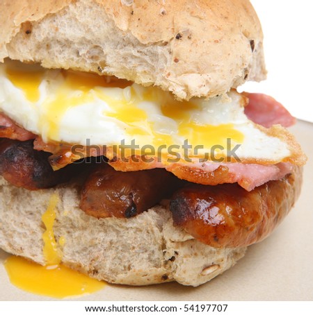 Bread roll with fried egg, bacon and sausages.