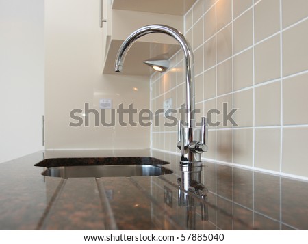 Kitchen sink with mixer tap recessed into granite work surface.