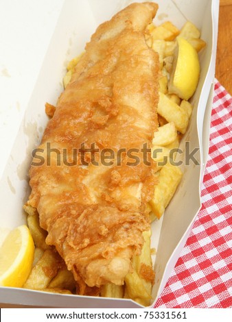 Fried cod fish with chips in takeaway carton.