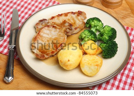 Pork steaks with roast potatoes, broccoli and gravy.