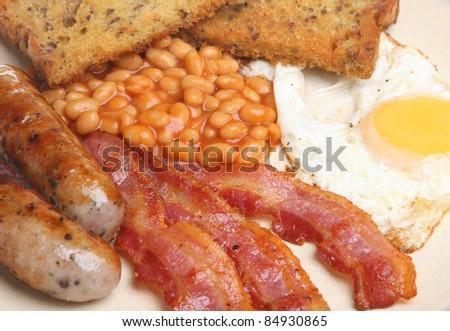 Fried breakfast with egg, bacon, sausages, baked beans and fried bead.