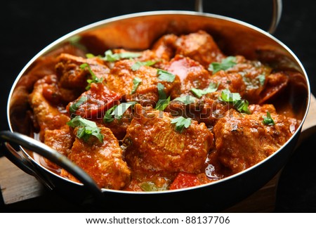 Indian chicken jalfrezi curry. Shallow DoF, focus on central chicken piece.