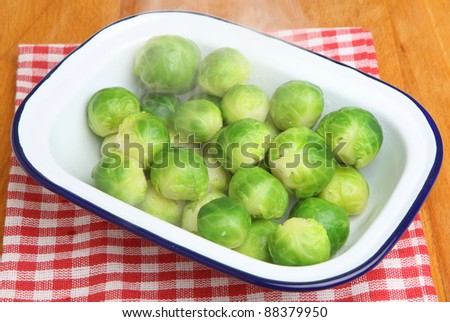 Cooked brussels sprouts in serving dish. Visible steam rising.