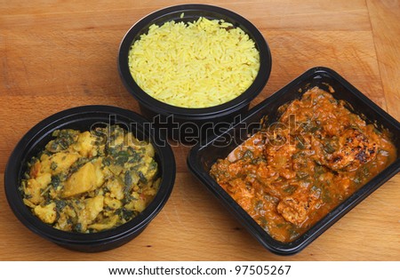 Indian convenience food of chicken massala curry, saag aloo and pliau rice.