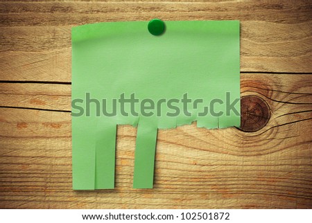 blank green note with tearable strips over wooden background, can be customized to enter some text, address and contact details