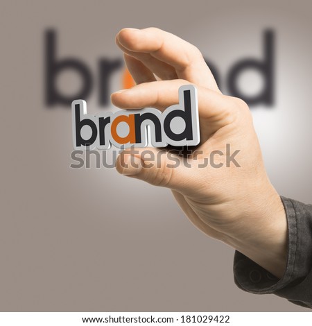 One hand holding the word brand over a beige background. Branding concept. The image is a composition between 2D illustration, 3D rendering and photography
