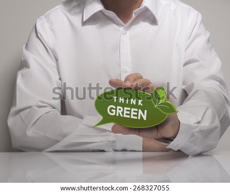 Image of a man hand holding speech balloon with the text think green, white shirt. Concept for ecology or environment preservation.