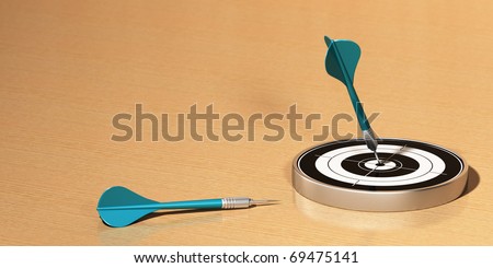Target and two darts on a wooden table, the first dart hit the center of the target the 2 darts are blue