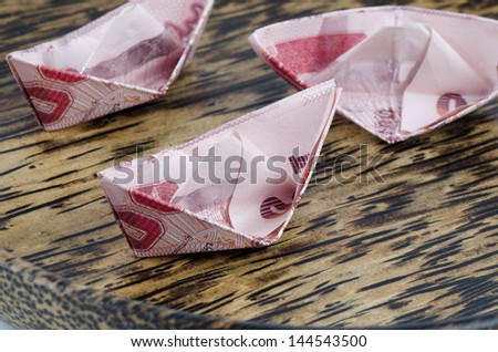 Thai money folded into the shape of a boat. On a white background.