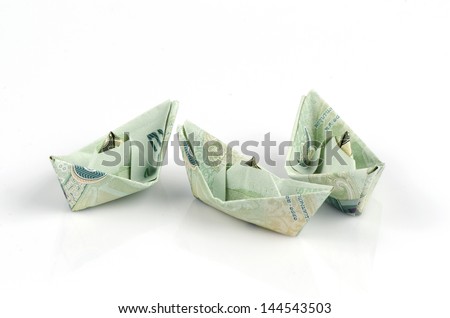 Thai money folded into the shape of a boat. On a white background.