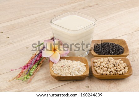 Soya milk and black sesame seeds on a white background. (Glycine max (L.) Merr.).
