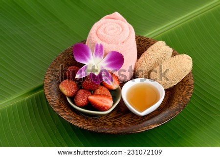 Face Mask with strawberry and honey on a background of green banana leaves.