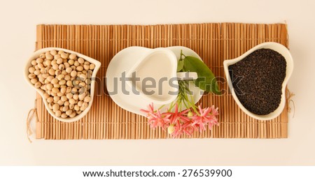 Soya milk and black sesame seeds on a white background. (Glycine max (L.) Merr.).