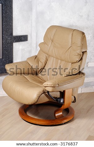 Modern leather arm chair with wooden stand near wall