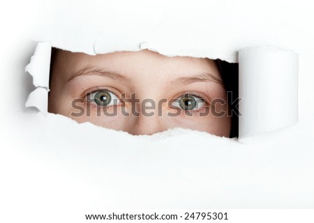 Young woman peeking through torn paper hole