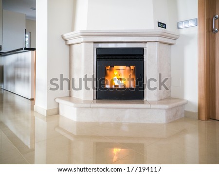 Pellet fire place alight and reflecting in a polished stone floor