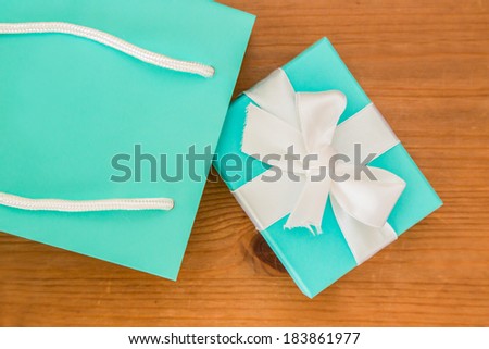 A blue gift box and blue gift bag on a wooden table