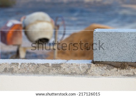 Breeze block wall construction with string line and cement mixer