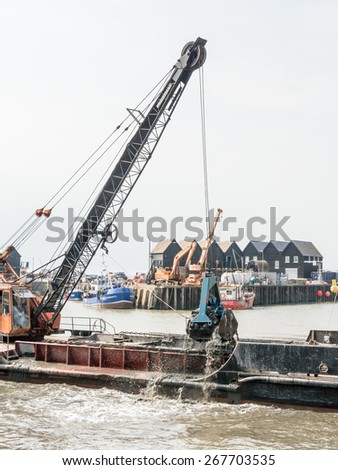 WHITSTABLE, UK - APRIL 8, 2015: Dredging taking place in Whitstable Harbour. The harbour requires periodic dredging. This is currently being carried out by a conventional means of grab and disposal.