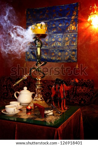 hookah with white smoke and tea cups on a table