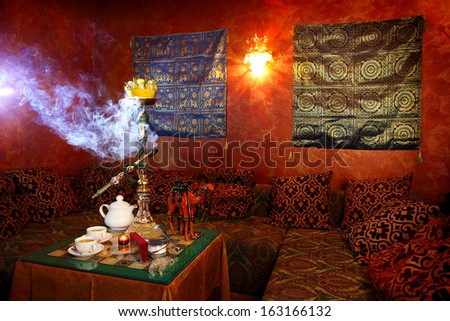 hookah with white smoke and tea cups on a table