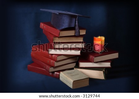 Bachelor\'s hat with books and candle on a dark blue background