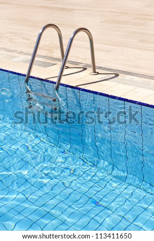 A view of a  light clear blue swimming pool with steel ladder.