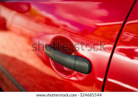 Red car door edge and black handle close-up.