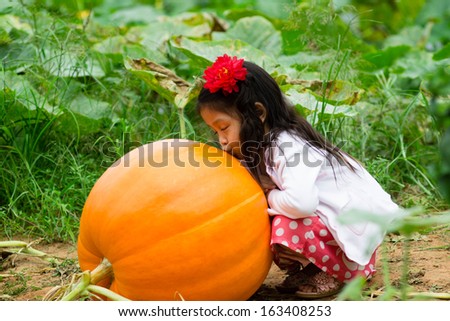Girl kissing a giant pumpkin.