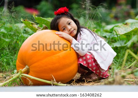 Girl hugging a giant pumpkin.