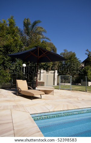 A luxury pool with deck chair and umberella.