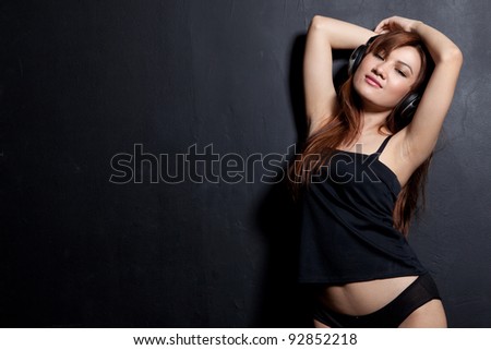 woman with headphone in black painted wall background
