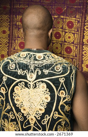 Rear view portrait of African-American mid-adult man wearing embroidered African vest.