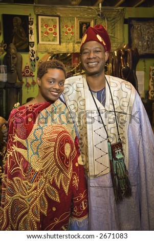 Portrait of smiling mid-adult African-American man and his young adult daughter wearing traditional African clothing.